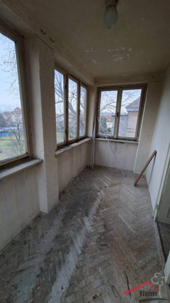 Glass veranda in a family house with a wooden decor floor and a view of the yard.