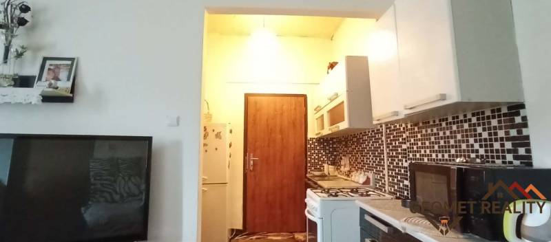 A kitchen with a counter and a stove in a 2-room apartment, mosaic tiles on the wall.