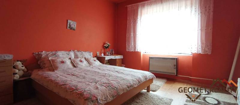 A bedroom with orange walls, a bed, and a carpet in a two-room apartment with decor.