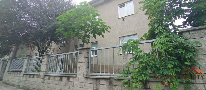 The exterior of the house with a stone fence and greenery on Partizánska Street in Lučenec.