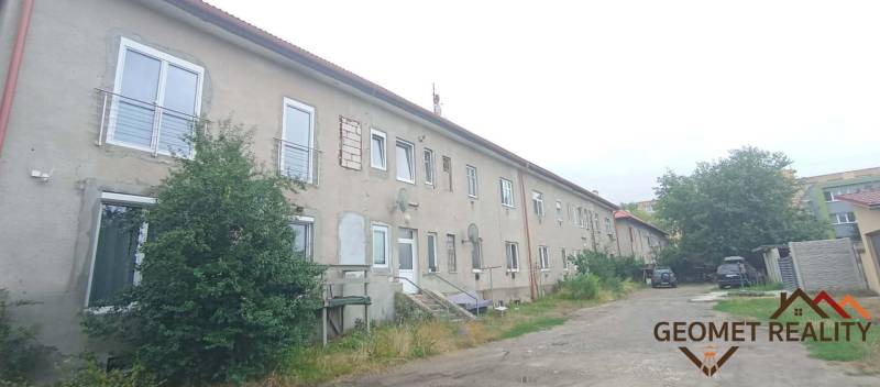 Apartment building on Partizánska Street in Lučenec with a simple facade and parking spaces.