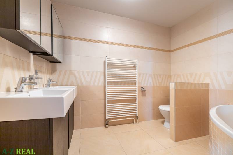 A bathroom in a family house with two sinks, a bidet, and a ladder radiator.