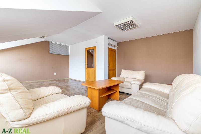 Living room with white armchairs, a wooden table, and a wooden-patterned floor in a family house.