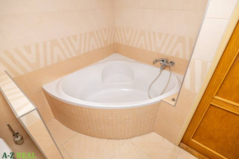 Bathroom with a corner bathtub and tiling in a family house.