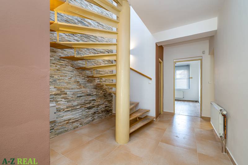 Interior of a family house with a spiral staircase and tiling, stone cladding on the wall.