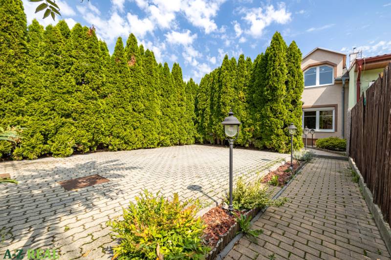 A family house on Bencúrova Street in Bratislava-Ružinov with a paved garden and thuja trees.