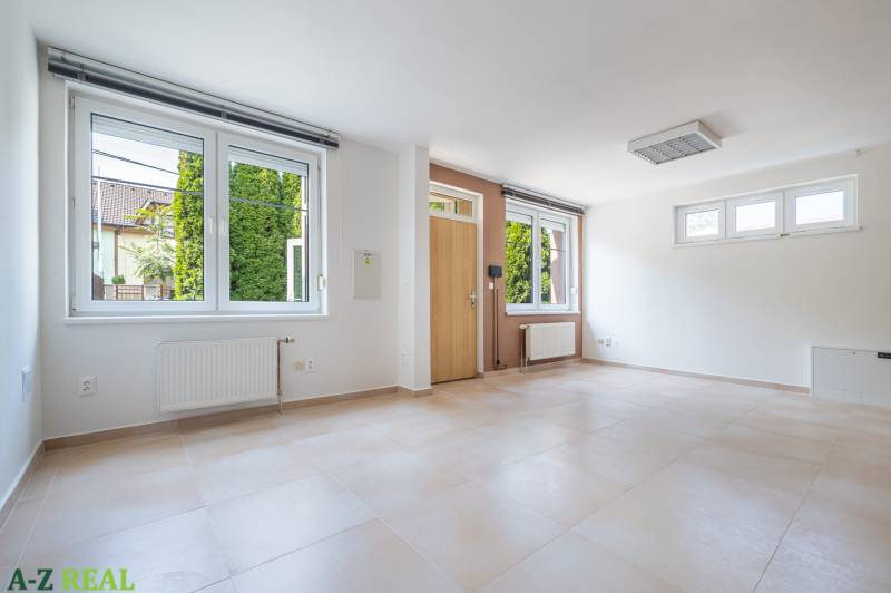 A spacious room with large windows, a wooden decor floor, entrance doors.
