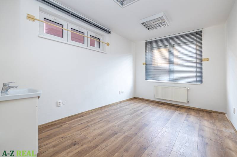 A room with windows and blinds, a sink, and a wooden decor floor in a family house.