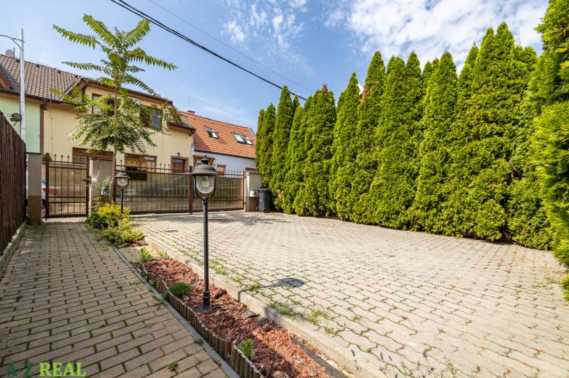 The family house on Bencúrova Street, Bratislava - Ružinov, has a paved courtyard with thuja trees.