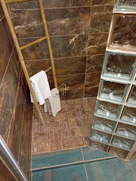 A bathroom in a cabin with ceramic tiles, a towel ladder, and a glass wall.
