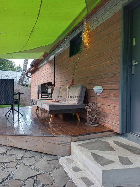 A cottage in Zvolen with an outdoor wooden terrace, a seating set, and stone paving.