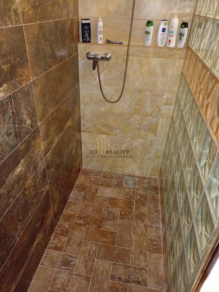 A shower corner in a cabin with stoneware tiles and glass bricks in a minimalist design.