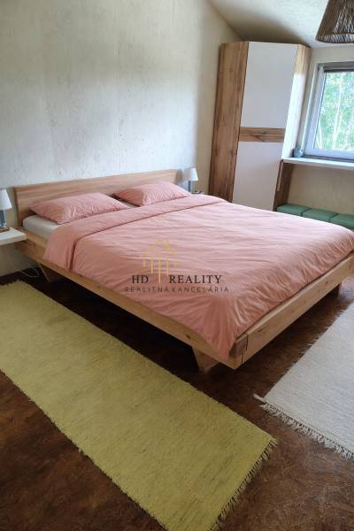 A bedroom in a cottage with a wooden bed, carpets, and a window to the garden.
