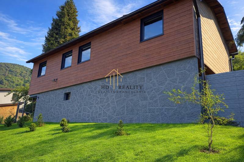 A cottage in the town of Zvolen with a stone and wooden facade surrounded by a manicured lawn.