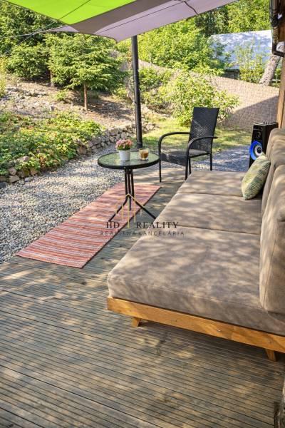 A cottage near Zvolen with a terrace, comfortable seating, a wooden-patterned floor, and a garden table.