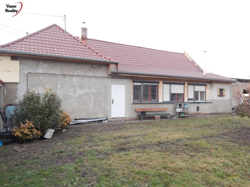 A family house in Kolárovo with a red roof and an unkempt garden.