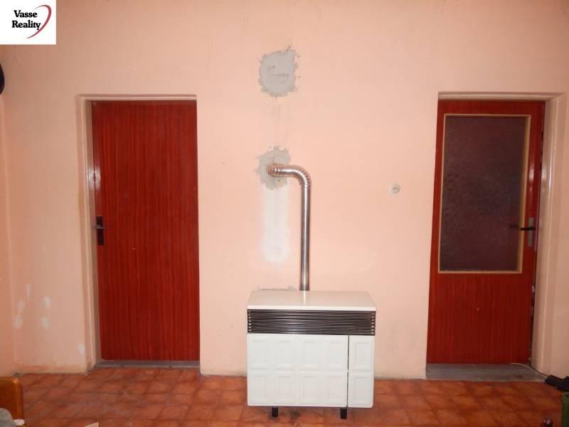 Interior of a family house with an older radiator, two doors, and tiles.