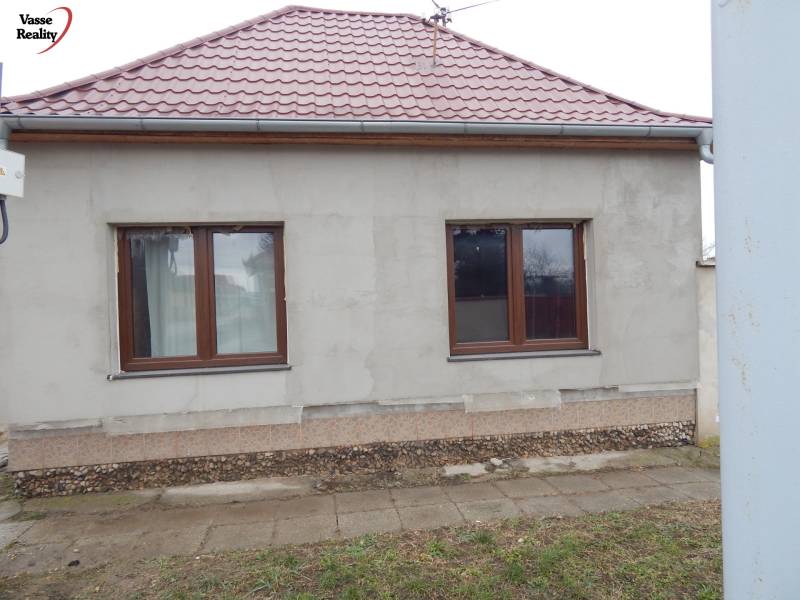 A family house in Kolárovo has a gray facade, a sloped red roof, and two windows.