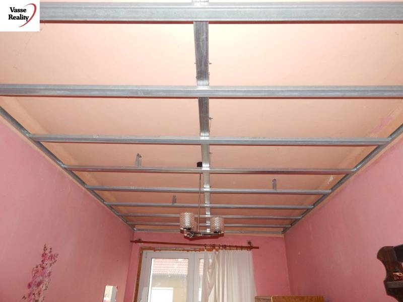 A room in a family house with a metal ceiling structure and pink walls.