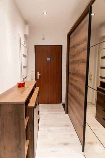 A hallway in a 2-room apartment with wooden furniture and a wooden decor floor.