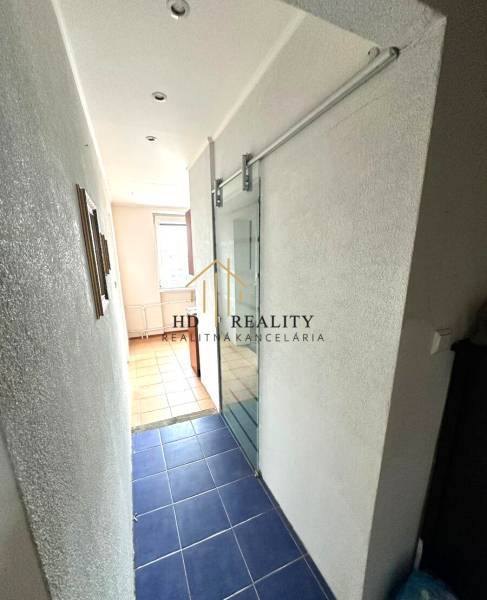 A narrow hallway in a 4-room apartment with glass doors, blue tiles, and a white wall.