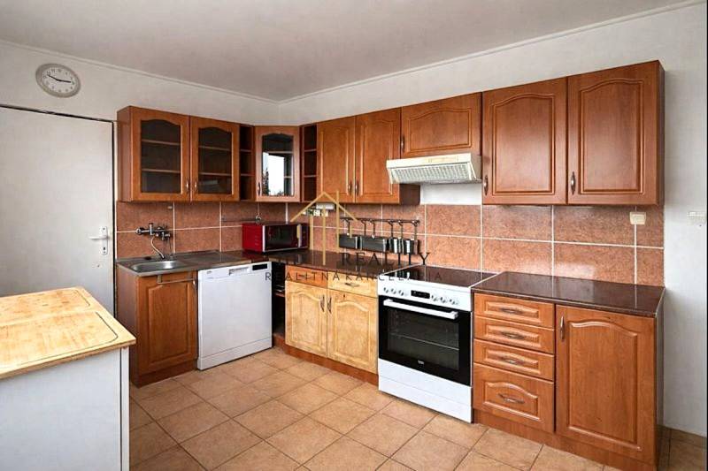 A kitchen with brown tiles and a countertop in a 4-room apartment.