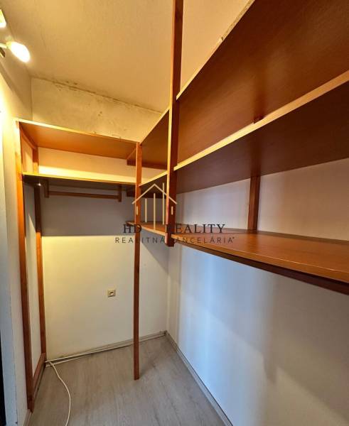 A wardrobe in a 4-room apartment with wooden shelves and a floor with a wooden decor.