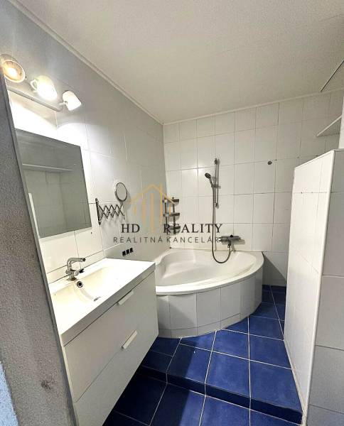 A bathroom with a shower, bathtub, and blue tiles in a 4-room apartment.