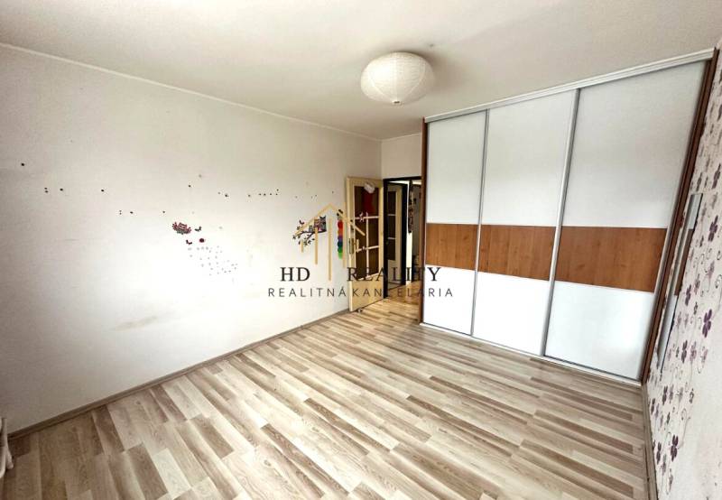 A bright room with a wardrobe and a wooden decor floor in a 4-room apartment.
