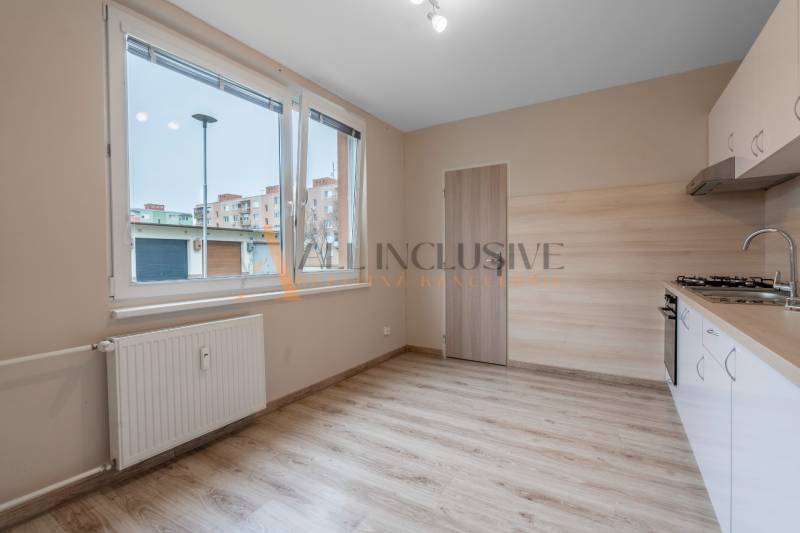 A kitchen in a one-room apartment with a wooden decor floor.