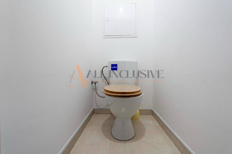 A simple toilet with light tiles in a studio apartment.