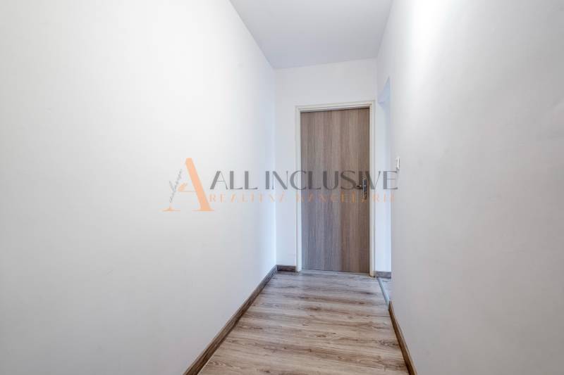 A hallway with light walls and a wooden decor floor in a studio apartment.