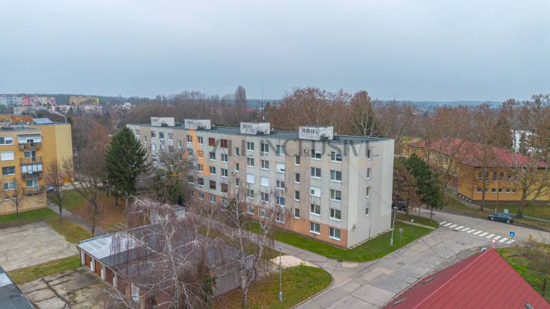 The portable building on Školská Street in Kolárovo surrounded by trees and other buildings.