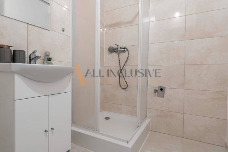 A bathroom with a white sink and a shower in a studio apartment.