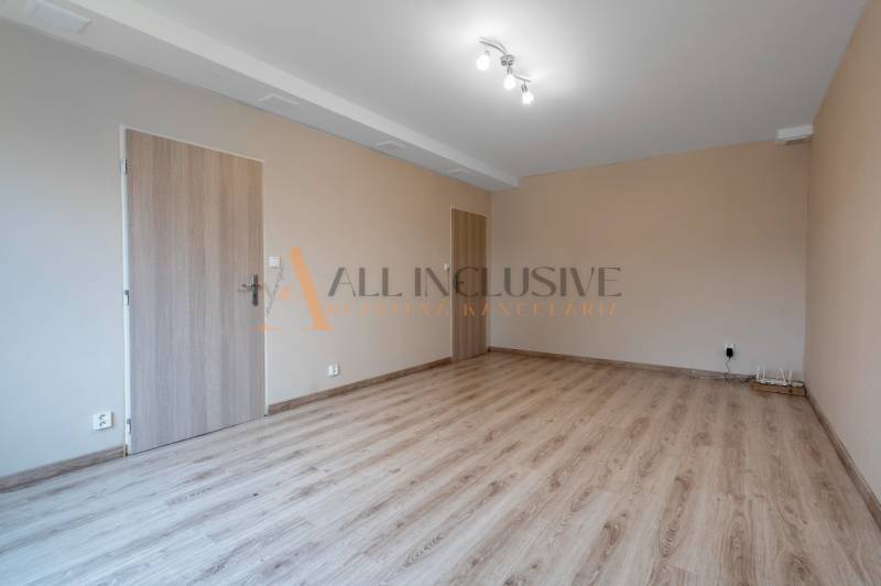 An empty room in a one-bedroom apartment, wooden decor flooring, light chandelier.