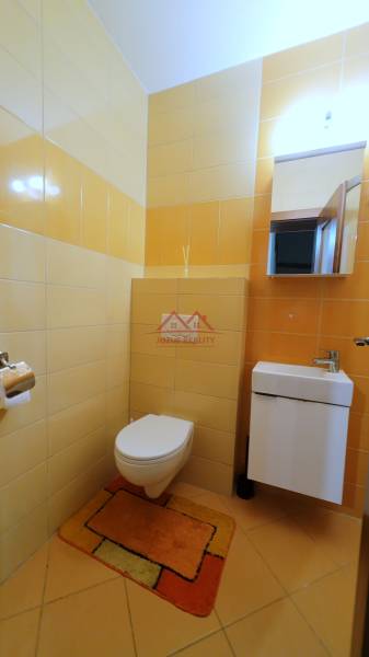 A bathroom in a family house with yellow tiles, a sink, and a mirror above it.