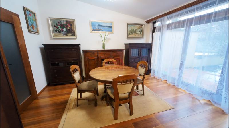 Dining room in a family house with wooden furniture, floor with wooden decor, paintings on the walls.