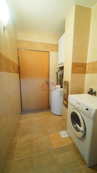 Laundry room in a family house with a washing machine and a boiler, tiled with light tiles.