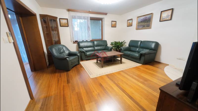 Living room in a family house with leather furniture and wood-patterned flooring.