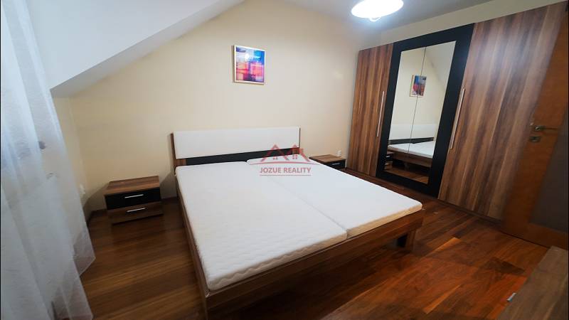 A bedroom in a family house with a bed and a wardrobe, floor with a wooden decor.