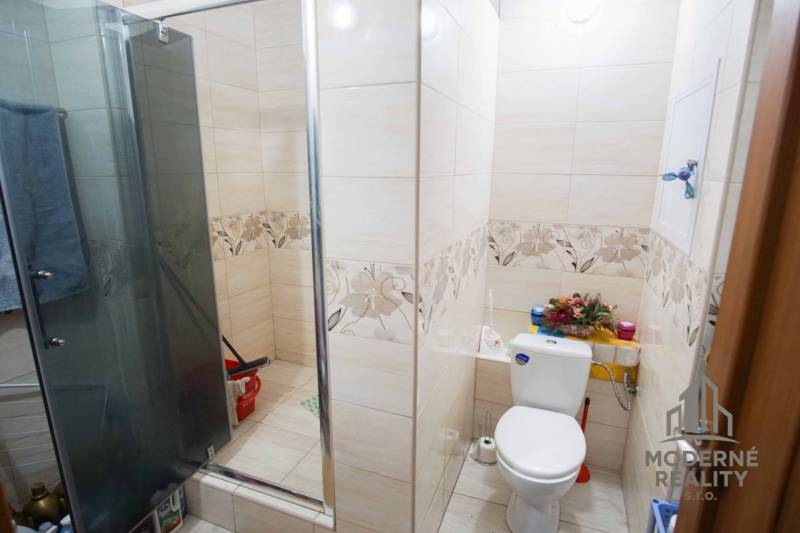 A bathroom with a shower and colorful tiles in a 2-room apartment.