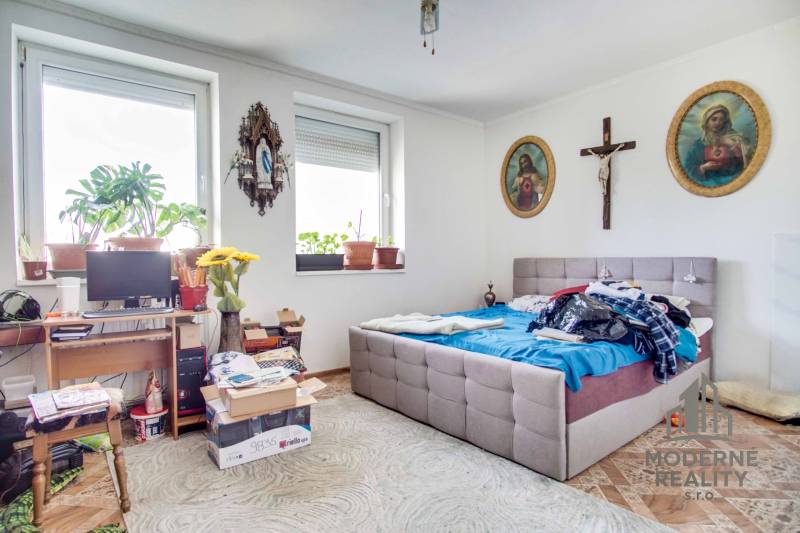 Bedroom in a 2-room apartment with plants, decorations, and a wooden-patterned floor.