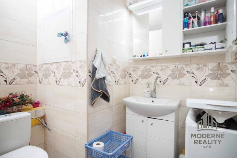 Bathroom in a 2-room apartment with patterned tiles, a sink, and storage space.