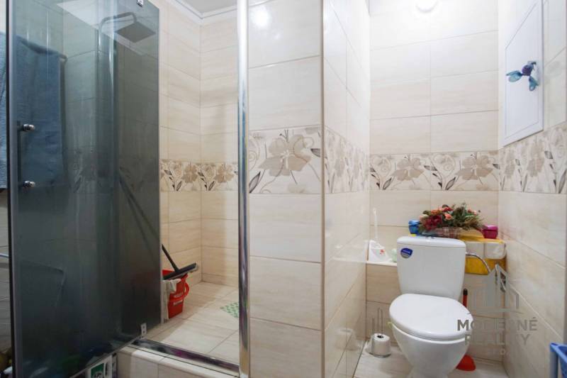 A bathroom in a 2-room apartment with modern tiles and a shower corner.