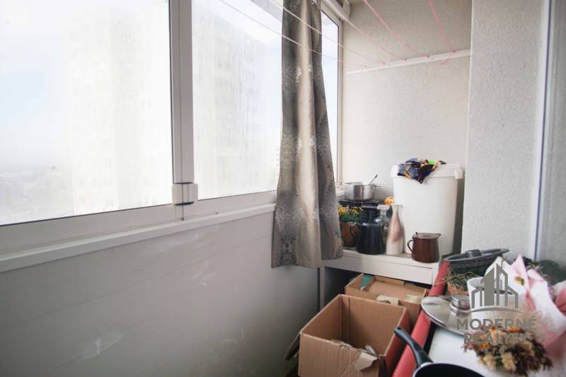 A glazed loggia in a 2-room apartment with lots of boxes and curtains for privacy.