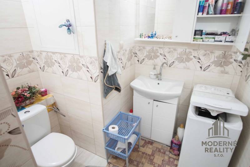 Bathroom in a 2-room apartment with a washing machine, cabinet, and decorative tiles.