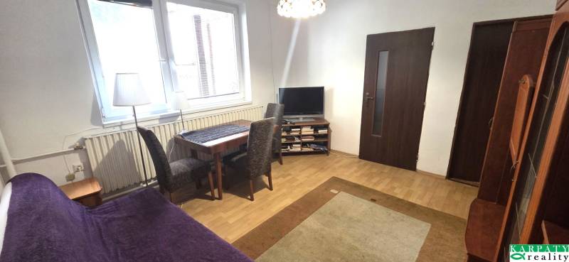 Living room in a family house with wood-patterned flooring, a television, and a dining table.