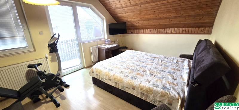 Bedroom in a family house with an exercise bike and a wooden decor floor.