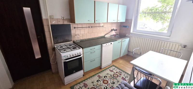 A kitchen with a gas stove, green cabinets, and a table in a family house.