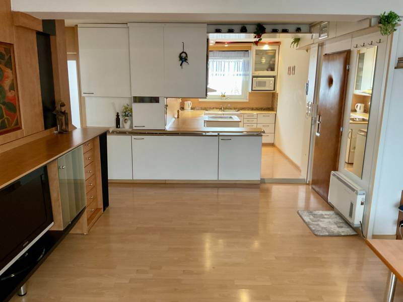 A kitchen in a 3-room apartment with a wood-patterned floor and built-in appliances.